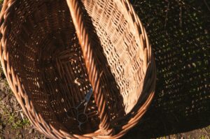 Top view of an empty wicker basket with scissors casting a shadow in sunny rural setting.